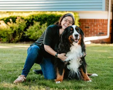 Nat kneeling on the grass with Benny, her Bernese mountain dog.